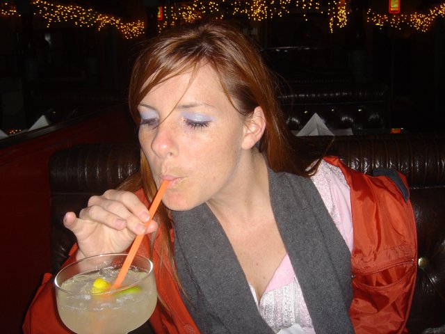 Young Woman Sipping Cocktail at Dimly Lit Bar