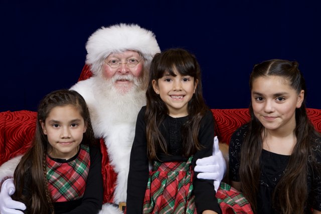 Santa Claus takes a picture with three adorable girls
