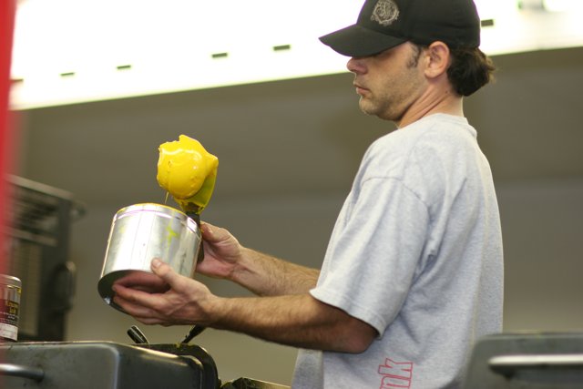 Holding a Can of Lemonade Caption: A man wearing a baseball cap and holding a yellow can of refreshing lemonade.