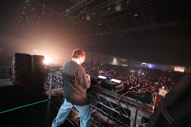 DJ Commanding a Massive Indoor Festival Crowd