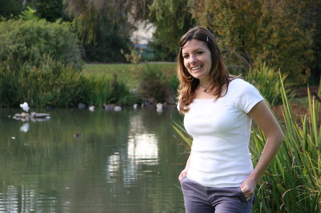 Smiling Woman Posing by Tranquil Park Pond
