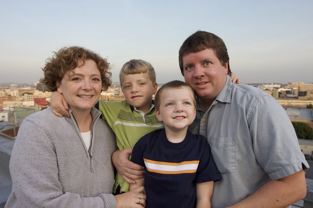 Family of Four Smiling on Urban Rooftop at Dusk