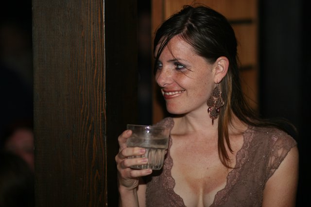 Woman Smiling with Drink at Evening Social Event