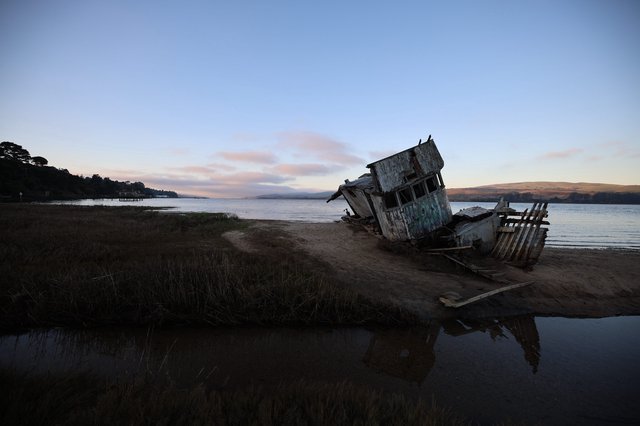 Abandoned Shipwreck at Dusk on Coastal Mudflats