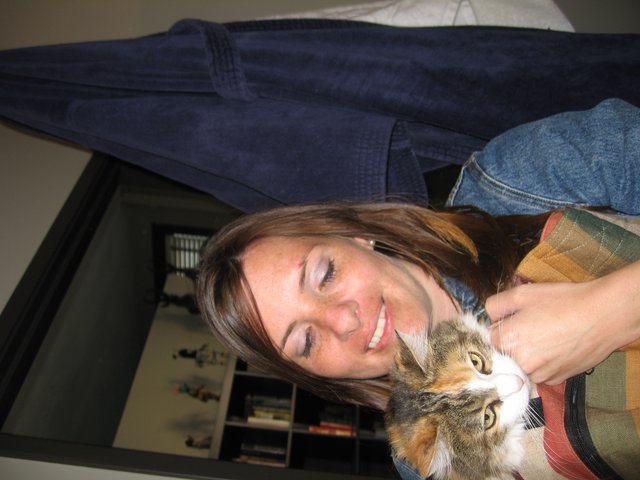 Woman Smiling Warmly While Cuddling Calico Cat