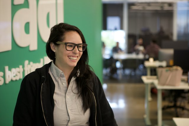 Woman in Glasses Smiling in front of Green Wall