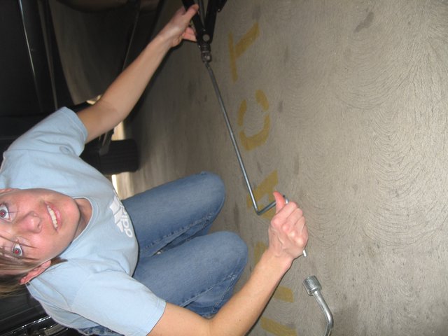 Woman Changes Tire with Jack in Parking Garage