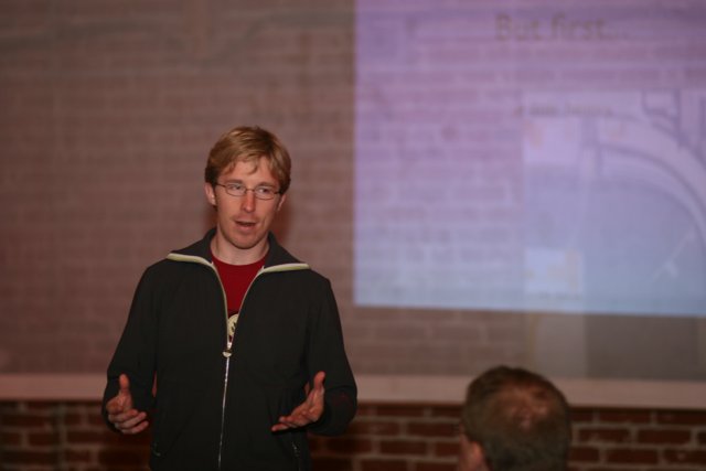 Man delivering lecture to a crowded room