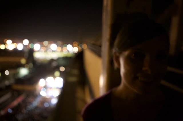 Silhouette Gazing at City Lights from Festival Balcony