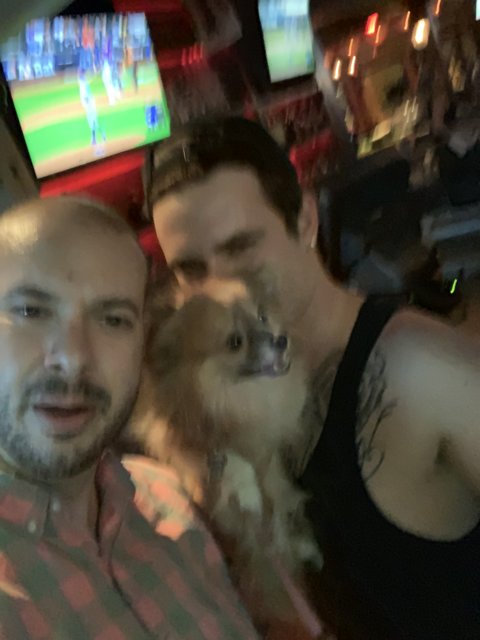 Two men and their furry friend unwind in a bar
