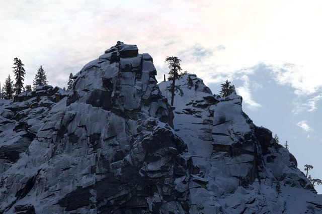Lone Climber Reaches Summit of Snow-Covered Rocky Peak