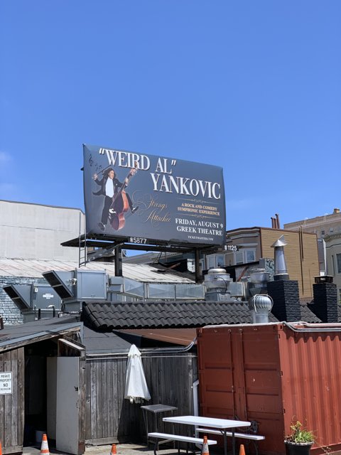 Weird Al Yankovic poses in front of Weby Al Vanko billboard on San Francisco rooftop