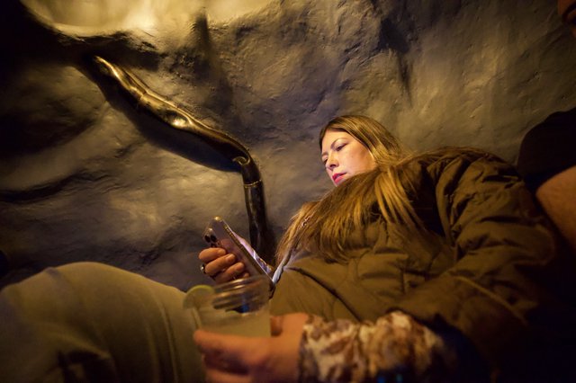 Woman Examining Mammoth Replica in Museum Cave Setting