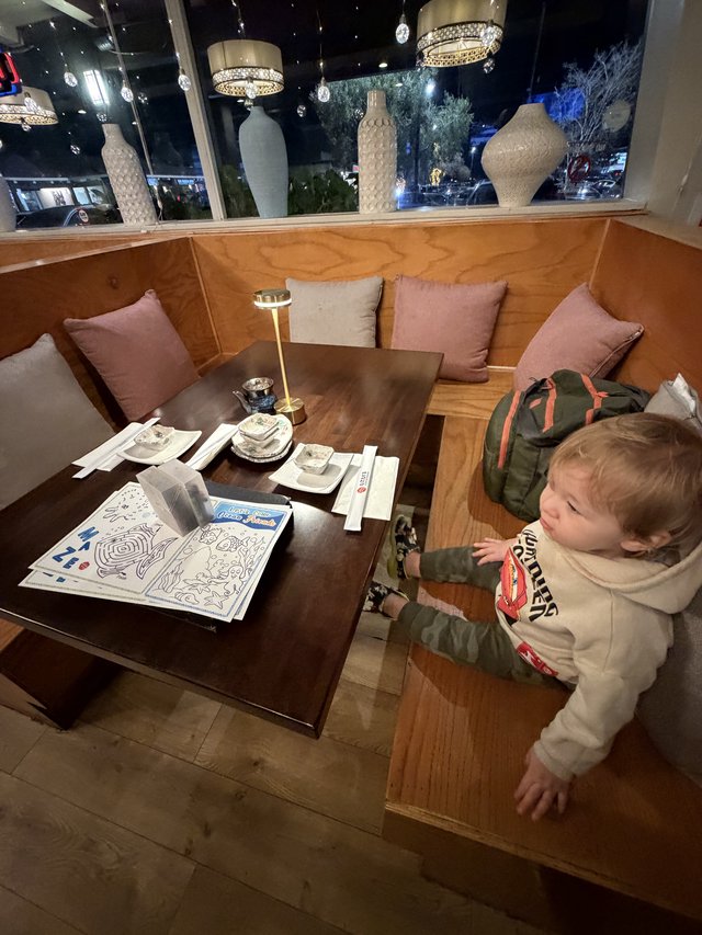 Toddler Exploring Restaurant Booth at Night