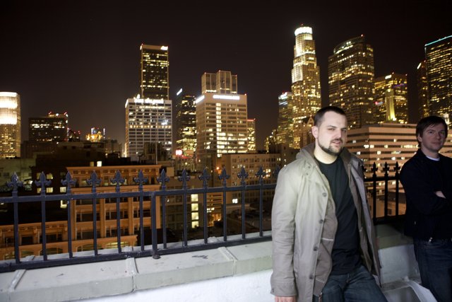 Two Men Overlooking the Urban Metropolis at Night