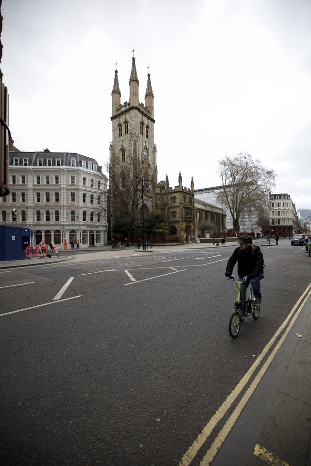 Cyclist Passes Historic Church on Overcast London Morning