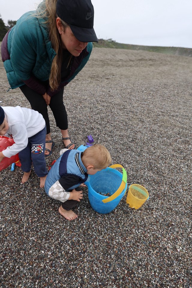 Toddler Explores Beach Bucket on Rocky Shore