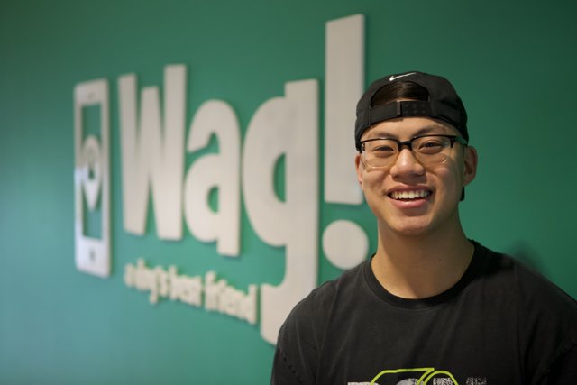 Young Man Poses in Front of Wag Logo