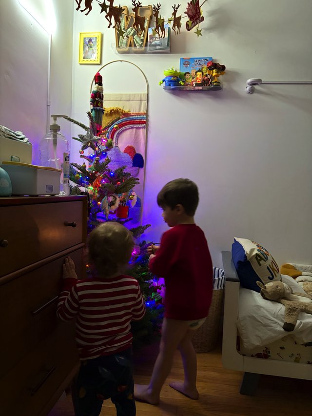 Children Decorating Small Christmas Tree in Bedroom