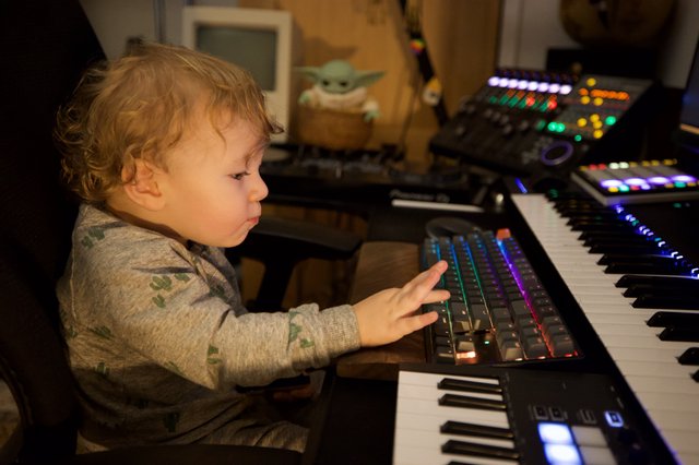 Young Child Exploring Music Production Equipment at Night