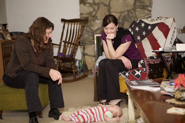 Two Women Admiring a Baby on the Floor