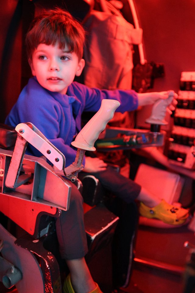 Young Boy Playing Arcade Motorcycle Game in Red Light