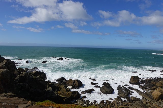A Breathtaking View of the Ocean and Sky from a Rocky Cliff