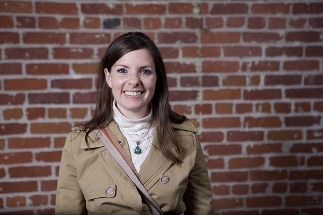 Smiling Woman Poses Against Rustic Brick Wall
