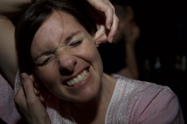 Woman Grimacing in Pain at Loud Nightclub