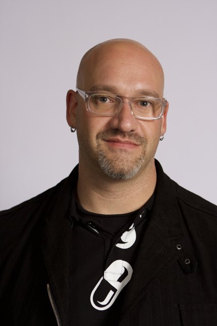 Bald man wearing glasses and a black shirt