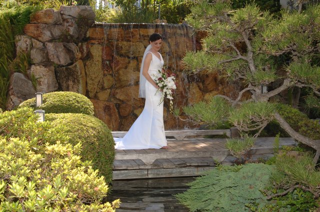 Bride Stands Elegantly Before Garden Waterfall