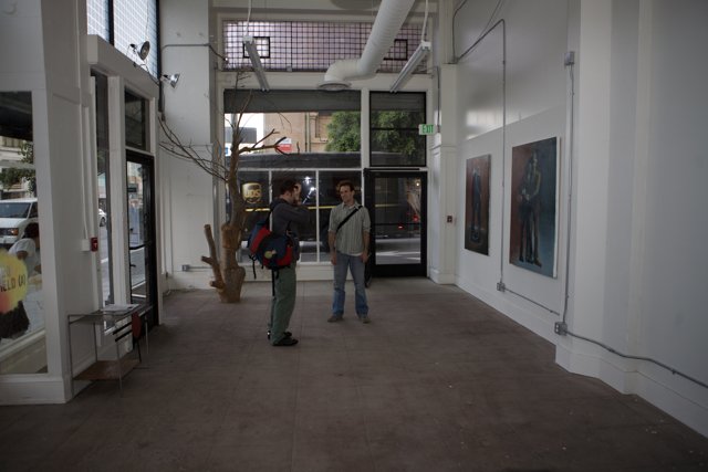 Two Men Admiring Art in Gallery Hallway