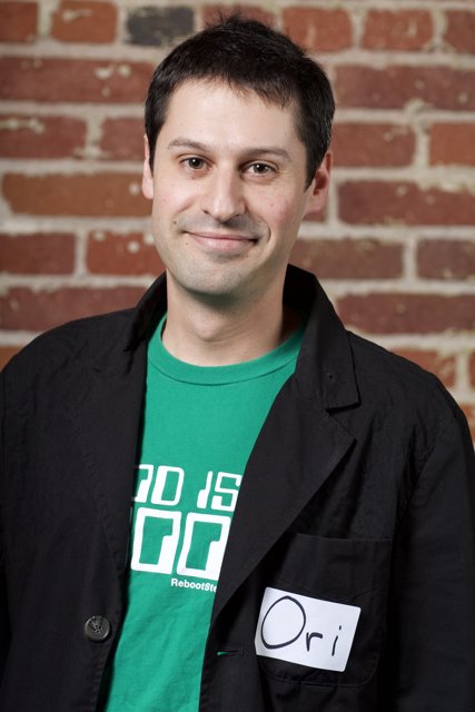 Smiling man in black coat and green shirt