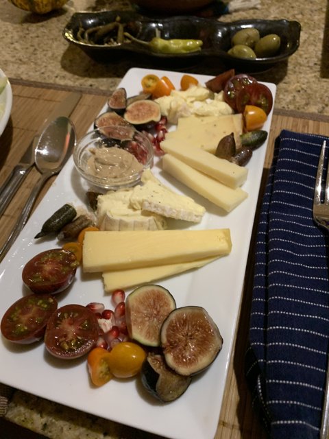 Antipasti Delight Caption: A plate of delicious antipasti consisting of cheese, tomatoes, and figs paired with a variety of savory meats and seasonings.