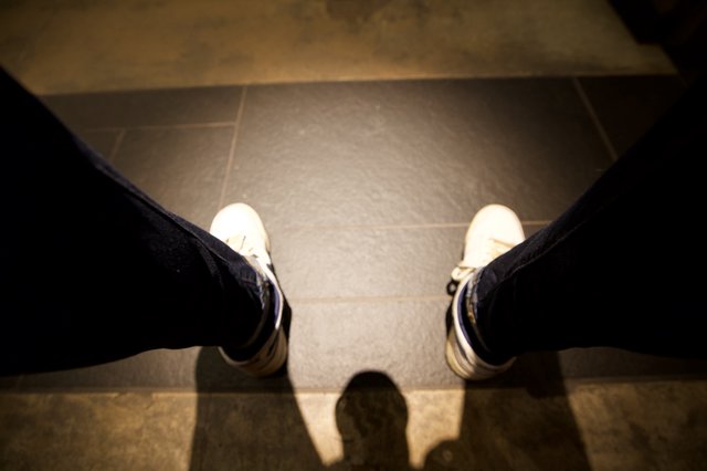 First-Person View: White Sneakers on Tiled Floor