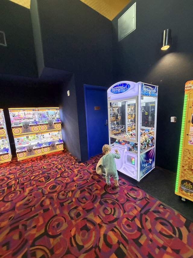 Child Playing Claw Machine at Entertainment Arcade