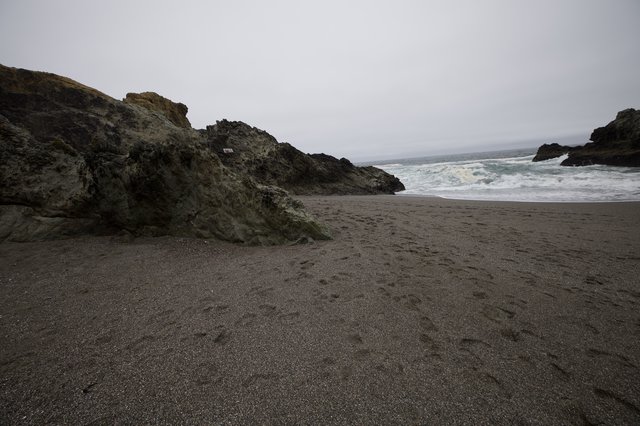Dark Sand Beach Meets Dramatic Coastal Rock Formation