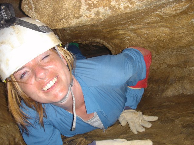Smiling Caver Squeezes Through Tight Underground Passage