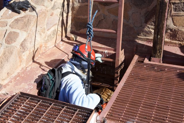 Man in Helmet and Harness Climbing Ladder