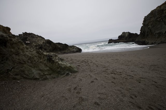 Rugged Cove Beach with Dark Sand and Crashing Waves