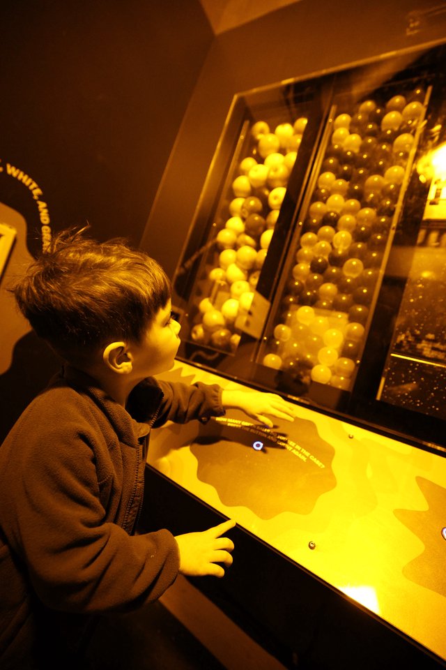 Child Exploring Interactive Ball Physics Exhibit at Science Museum