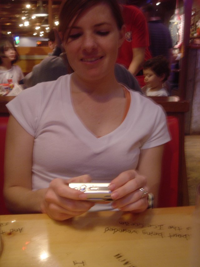 Woman Smiling at Digital Camera in Restaurant Booth