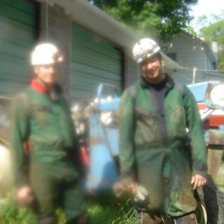 Two workers in green coveralls inspecting a tire