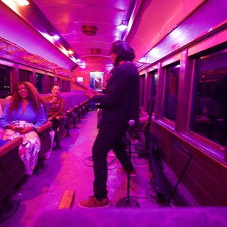 Live Music Performance in Vibrant Purple-Lit Train Car