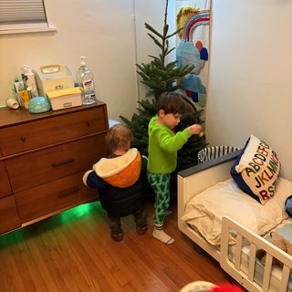 Two Children Decorating Christmas Tree in Bedroom