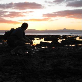 Kneeling by the Ocean at Sunset