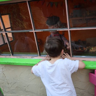 Child Peering into Window of Colorful Playhouse
