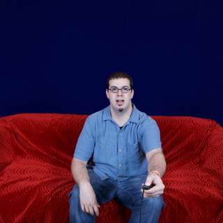 Dave B lounges on a red velvet sofa