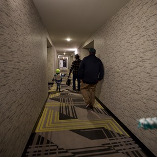Family Walking Down Modern Hotel Corridor with Geometric Carpet