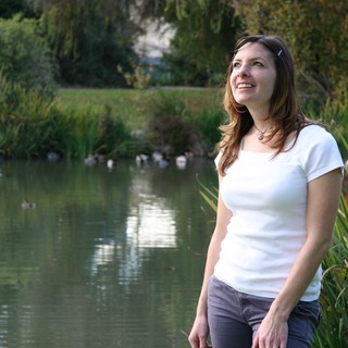 Woman Gazing Skyward by a Tranquil Park Pond